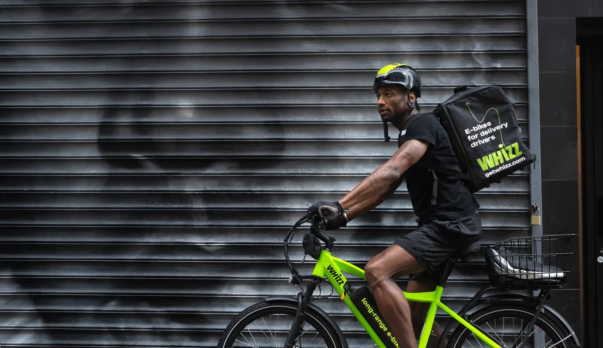 Whizz delivery rider on a company e-bike with a Whizz delivery backpack